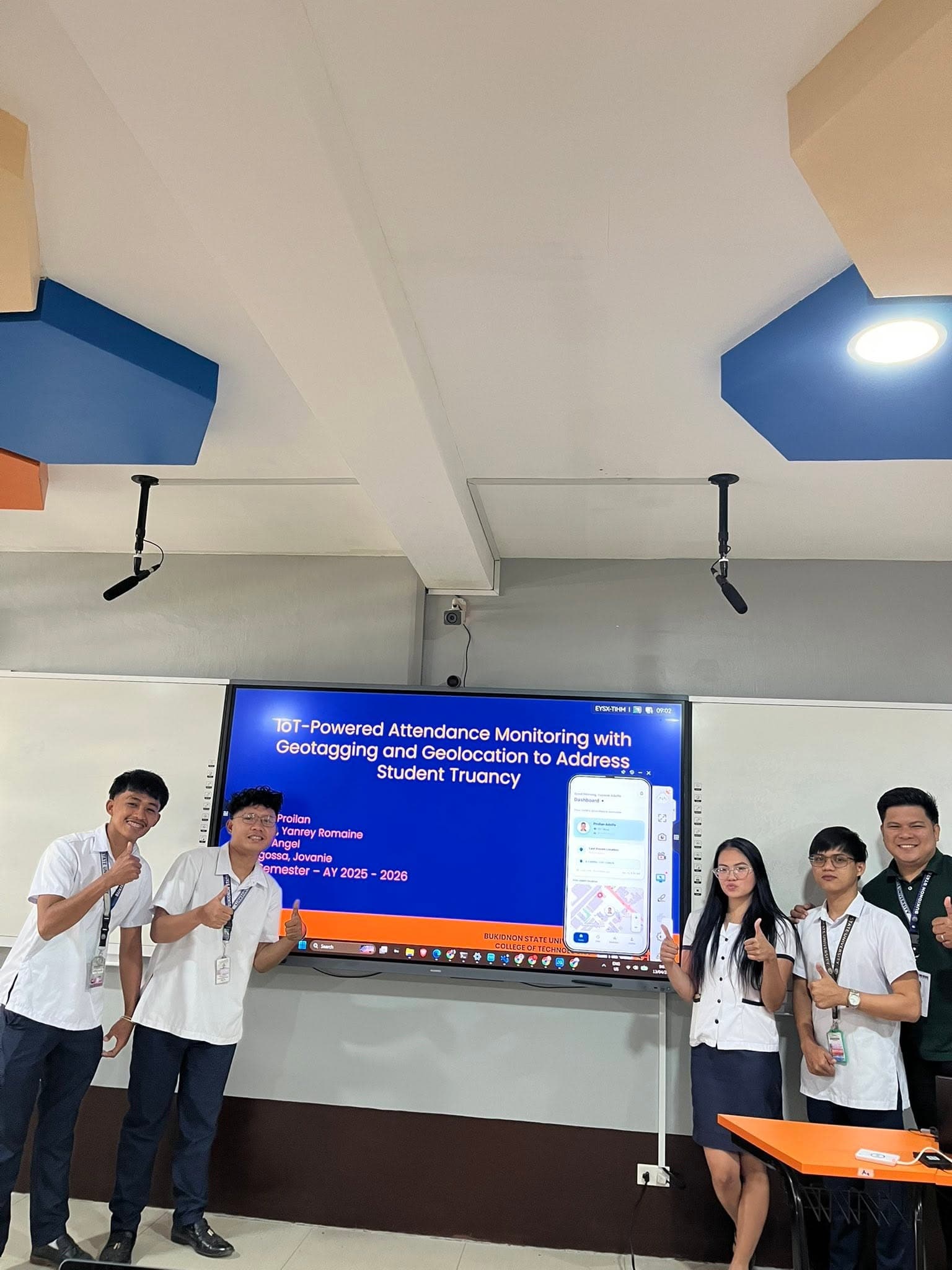 The team giving a thumbs up after presenting the capstone on the classroom screen
